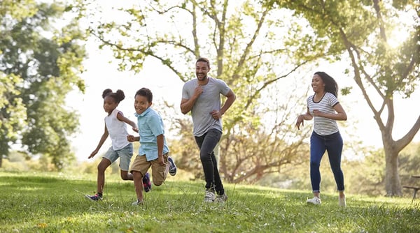 A family runs and laughs through a park